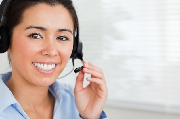 Retrato de uma mulher bonita com um fone de ouvido ajudando clientes enquanto está sentado