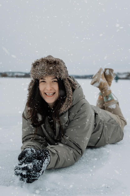 retrato de uma mulher bonita deitada em um lago de neve gelada desfrutando de um belo clima de inverno e posando para uma foto