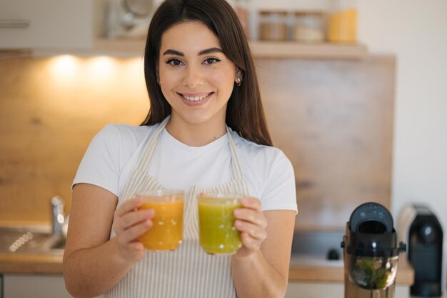 Foto retrato de uma mulher bonita segurando dois copos de bebidas diferentes nas mãos bebida vegana saudável