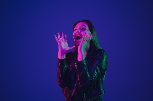 Retrato de uma mulher caucasiana isolado no fundo azul do estúdio em luz de néon