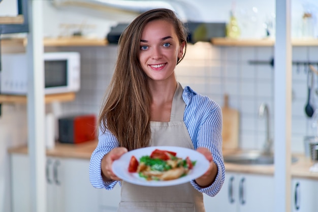 Retrato de uma mulher chefe de cozinha feliz fofa alegre sorridente com um prato de salada fresca