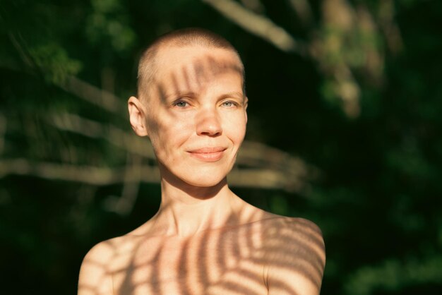 Retrato de uma mulher com a cabeça raspada com sombras de uma samambaia na foto natural da floresta