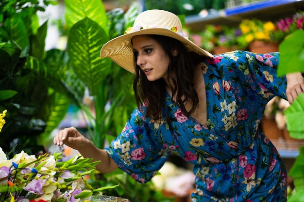 Retrato de uma mulher com chapéu de palha procurando algumas plantas em uma floricultura