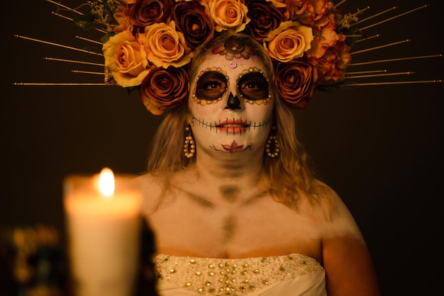 Retrato de uma mulher com maquiagem de catrina vestindo um vestido de noiva Vela e crânio borrados em primeiro plano