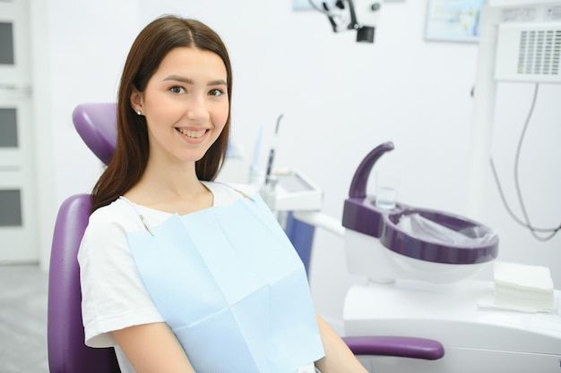 Retrato de uma mulher com um sorriso, sentado na cadeira odontológica no consultório odontológico