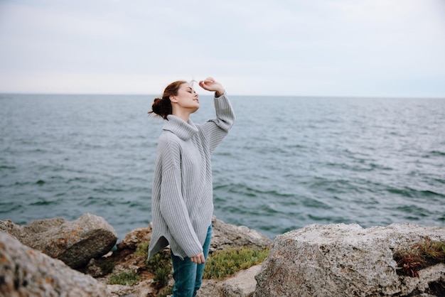 Retrato de uma mulher com uma camisola cinzenta em uma costa rochosa natureza estilo de vida foto de alta qualidade
