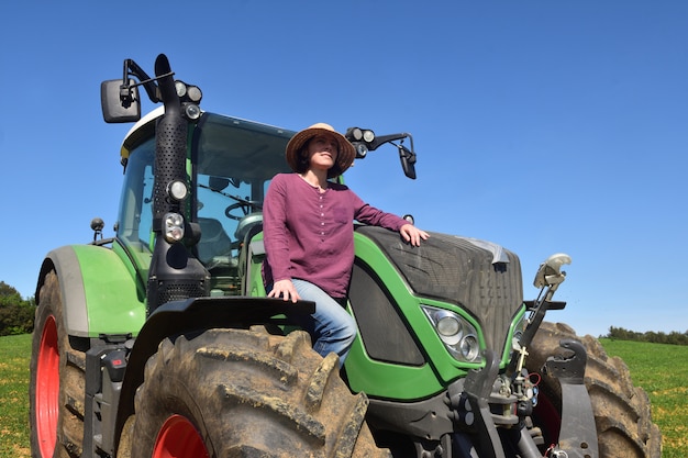 Foto retrato de uma mulher de fazendeiro e trator no campo