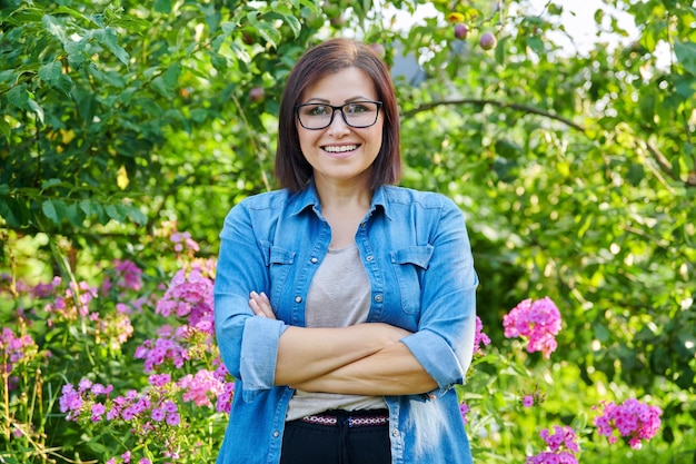 Retrato de uma mulher de meia idade confiante sorridente com braços cruzados no jardim