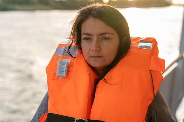 Retrato de uma mulher de meia-idade em um colete salva-vidas laranja marinho Uma segurança de perfuração na água