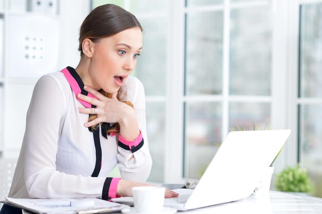 Retrato de uma mulher de negócios agradável com um laptop no escritório