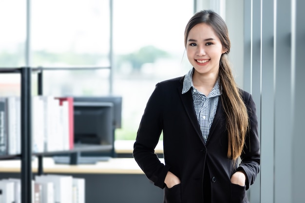 Retrato de uma mulher de negócios asiática madura e alegre em No fundo da sala de escritório, a empresa expressou confiança, coragem e conceito de sucesso