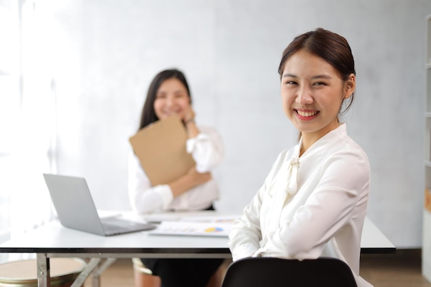 Retrato de uma mulher de negócios asiática sorridente e feliz trabalhando com colegas no escritório