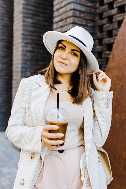 Foto retrato de uma mulher de negócios bem-sucedida segurando uma xícara de bebida gelada na mão a caminho do trabalho na rua da cidade