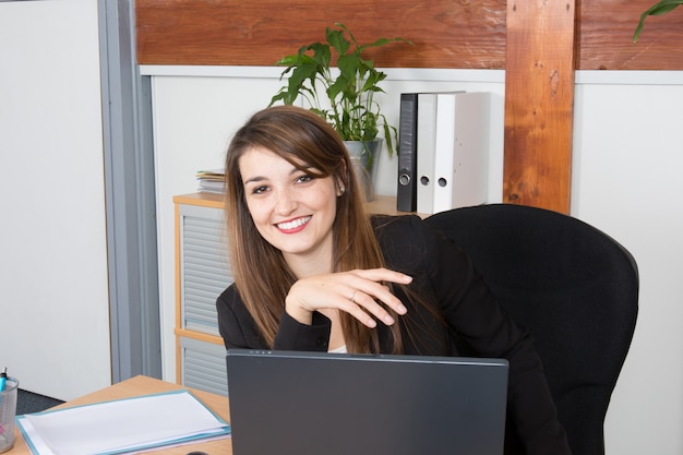 Retrato de uma mulher de negócios elegante com laptop em um escritório brilhante