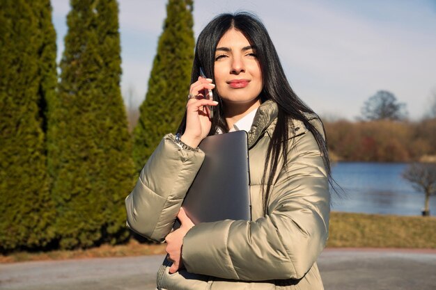 Retrato de uma mulher de negócios europeia que está falando ao telefone na rua