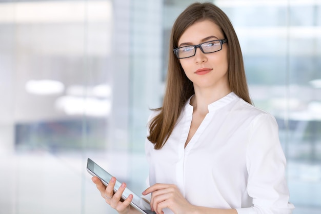 Retrato de uma mulher de negócios moderna trabalhando com computador tablet no escritório