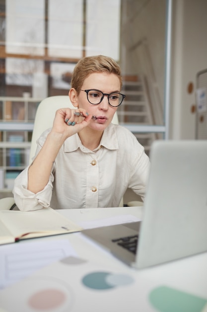 Retrato de uma mulher de negócios moderna usando laptop enquanto faz networking no escritório