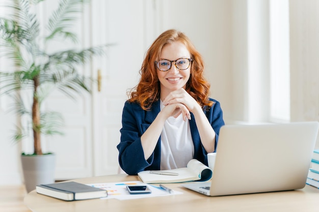 Retrato de uma mulher de negócios sorridente sentada à mesa no escritório