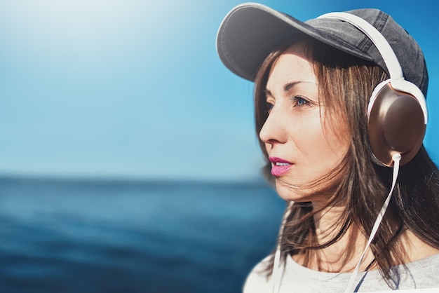 retrato de uma mulher de óculos escuros com um boné que gosta de música no fundo do mar.