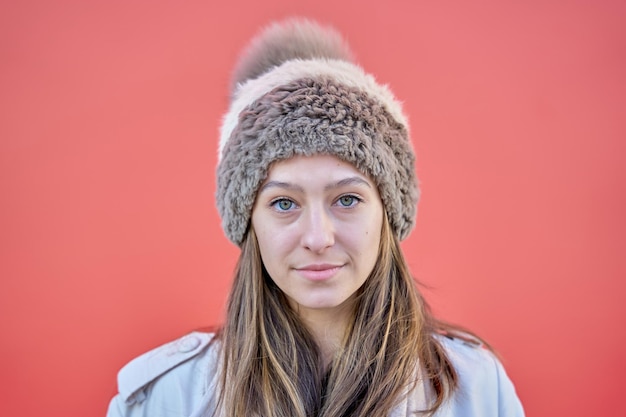 retrato de uma mulher de olhos azuis, olhando para a câmera com um gorro de lã isolado em fundo vermelho