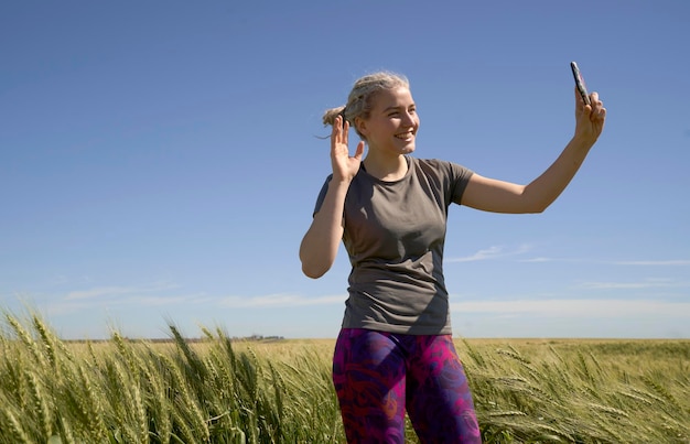 Foto retrato de uma mulher de pé falando no celular em um campo de trigo