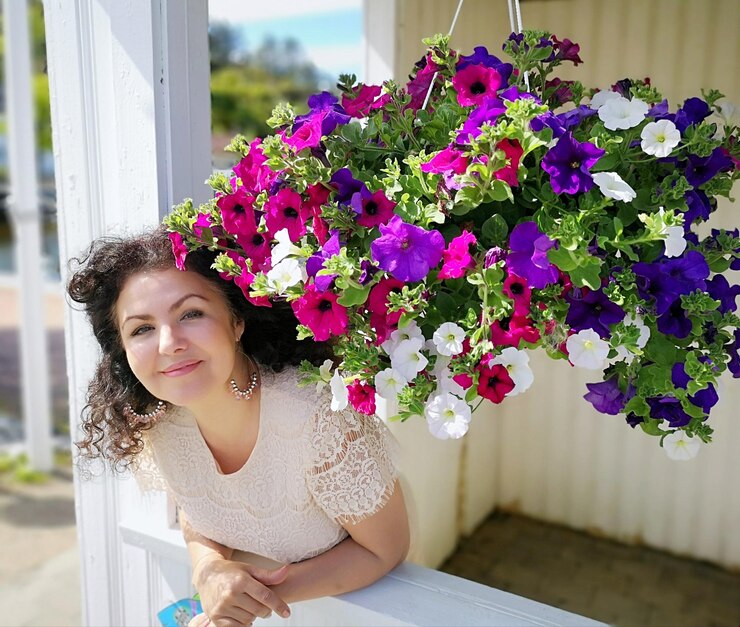 Foto retrato de uma mulher de pé junto a flores coloridas na varanda