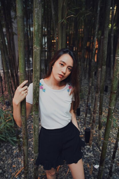 Foto retrato de uma mulher de pé junto a um tronco de bambu no parque