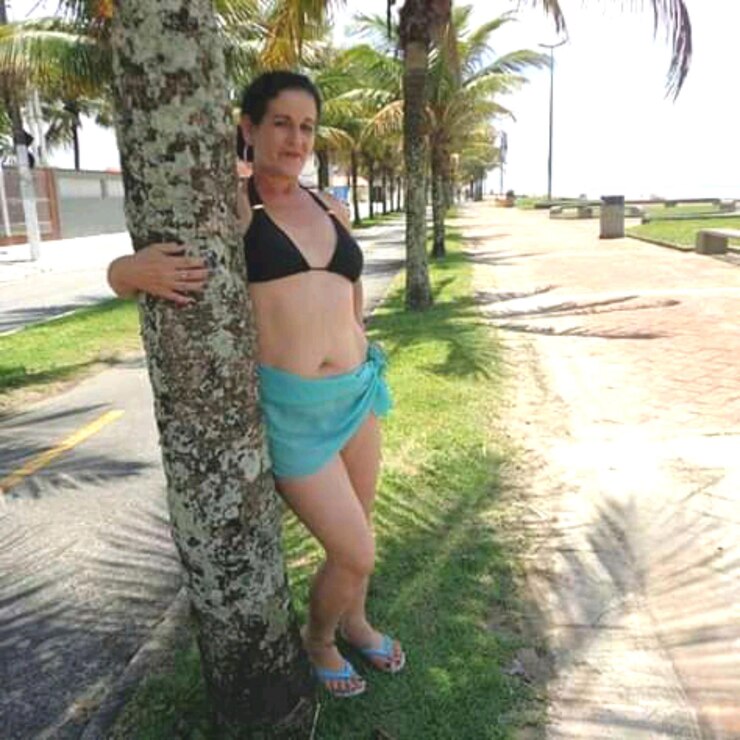 Foto retrato de uma mulher de pé junto ao tronco de uma árvore
