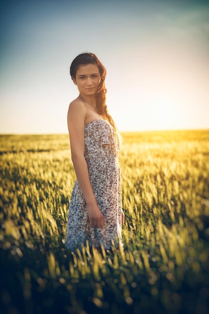 Retrato de uma mulher de pé no meio de plantas no campo durante o pôr do sol