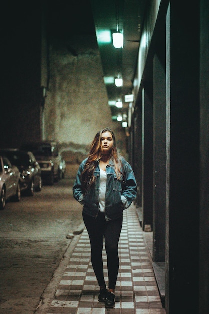 Retrato de uma mulher de pé perto de um edifício à noite