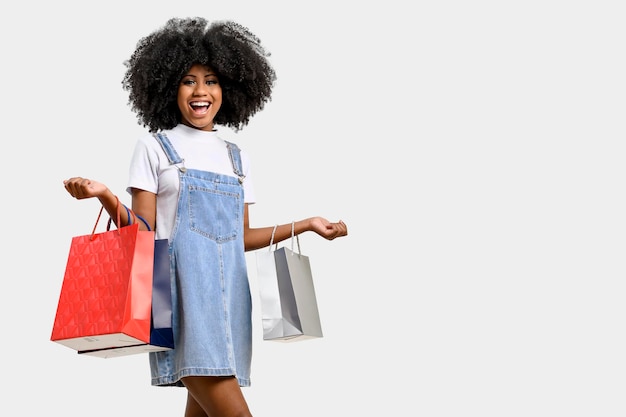 Retrato de uma mulher de pele morena jovem sorridente ela segura sacolas de compras, isoladas em fundo cinza.