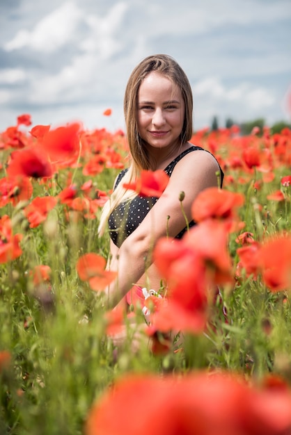 Retrato de uma mulher deslumbrante em roupas esportivas posando enquanto caminhava no incrível campo de papoulas em uma noite quente de verão. Aproveite a liberdade