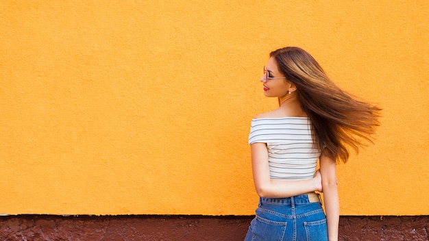 Foto retrato de uma mulher elegante em óculos de sol com maquiagem e cabelos a voar. urbano