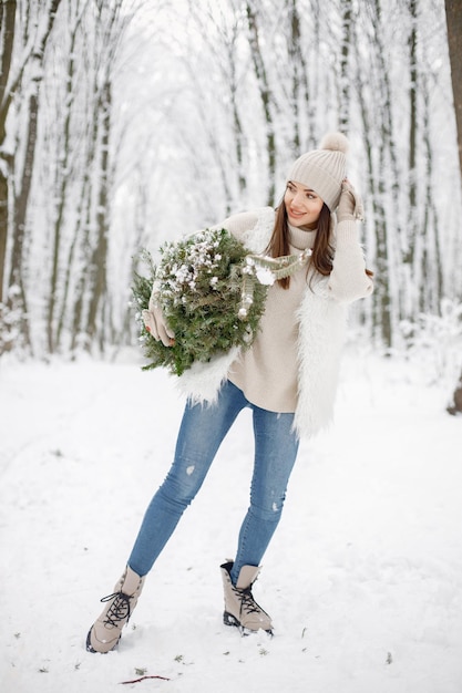 Retrato de uma mulher em pé na floresta de inverno e posando para uma foto