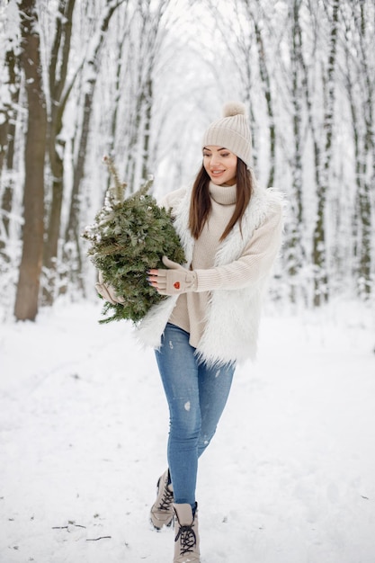 Retrato de uma mulher em pé na floresta de inverno e posando para uma foto