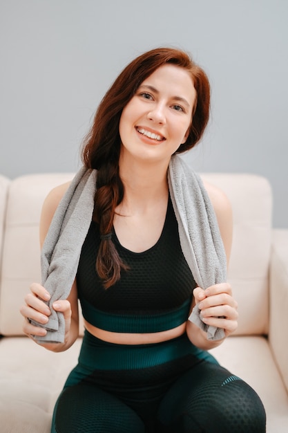 Retrato de uma mulher em roupas esportivas com uma toalha após um treino intensivo em homeconcept de saúde ...