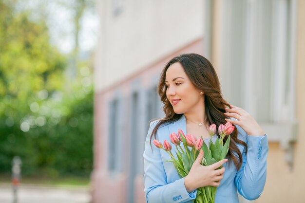 Retrato de uma mulher em um terno azul com um buquê de tulipas