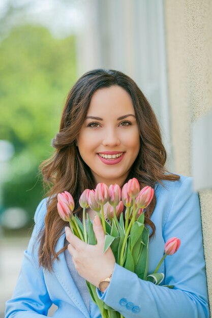 Retrato de uma mulher em um terno azul com um buquê de tulipas