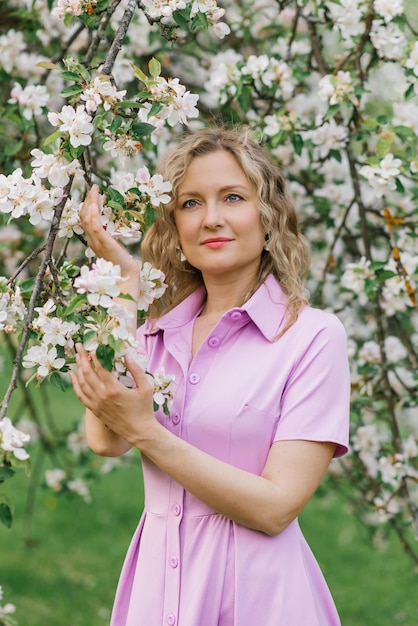 Retrato de uma mulher em um vestido lilás em um jardim florescente na primavera