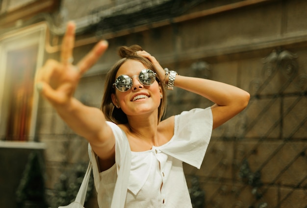 Retrato de uma mulher encantadora e alegre em roupas da moda e óculos escuros