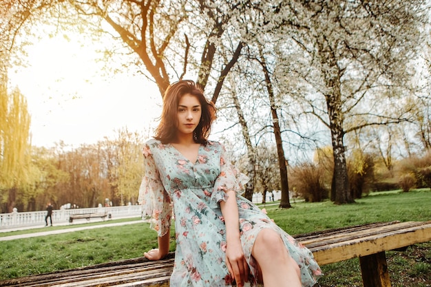 Retrato de uma mulher encantadora posando perto de flores de cerejeira de maçã florescendo flores no jardim