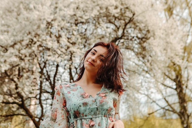 Foto retrato de uma mulher encantadora posando perto de flores de cerejeira de maçã florescendo flores no jardim