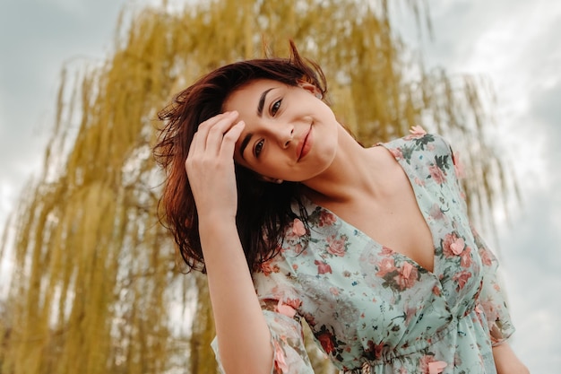 Retrato de uma mulher encantadora posando perto de flores de cerejeira de maçã florescendo flores no jardim