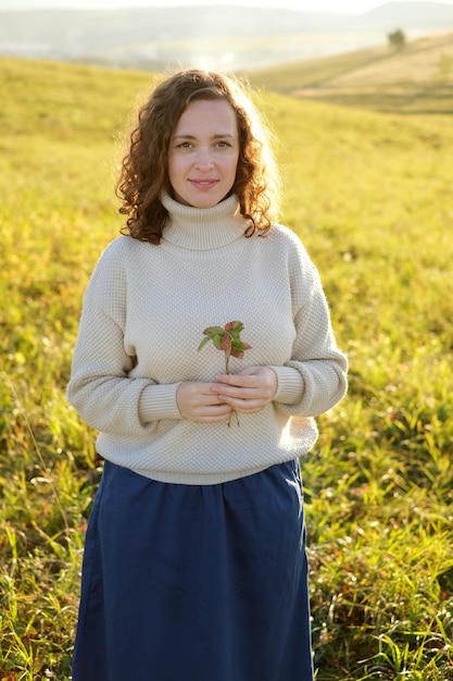 Retrato de uma mulher encaracolada de cabelos escuros sorrindo em pé na paisagem de campo