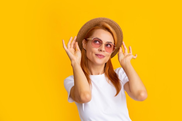 Retrato de uma mulher engraçada em óculos de sol elegantes e chapéu de palha em fundo amarelo