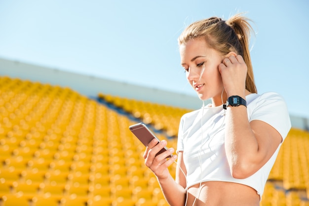Retrato de uma mulher esportiva usando smartphone no estádio