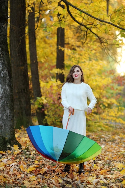 Retrato de uma mulher está de pé na floresta de outono, os galhos das árvores com folhagem amarela