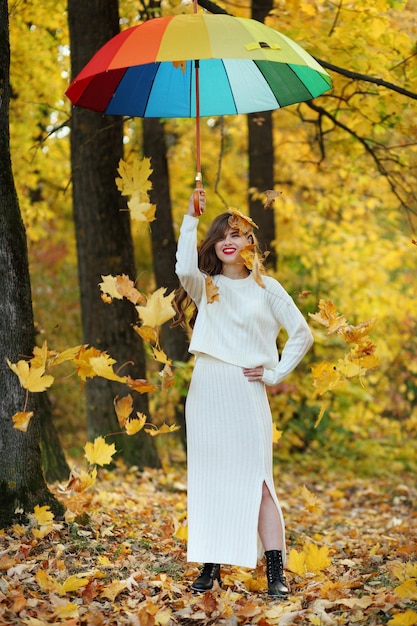 Retrato de uma mulher está de pé na floresta de outono, os galhos das árvores com folhagem amarela