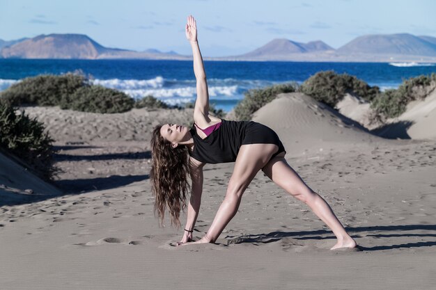 Retrato de uma mulher fazendo yoga na praia