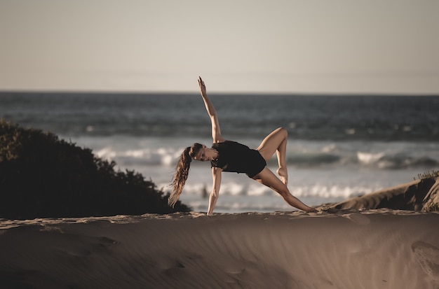 Retrato de uma mulher fazendo yoga na praia